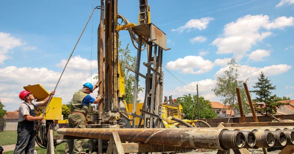 Twee installateurs die bezig zijn met een grondboring: de werken drijven de prijs voor installatie omhoog. 
