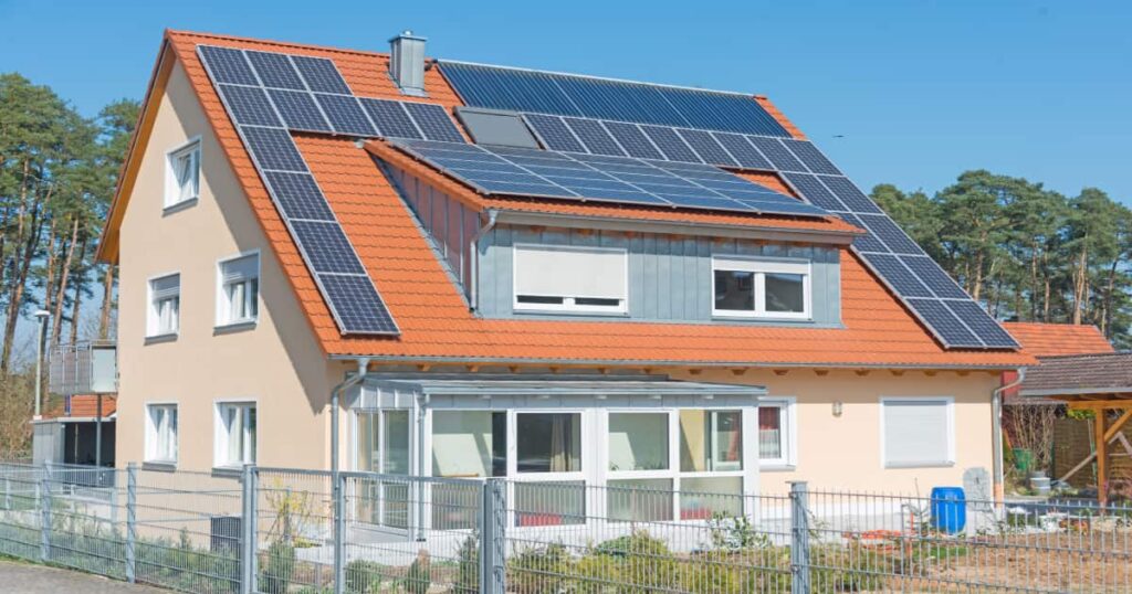 Een huis met een hellend dak waar zonnepanelen op geplaatst zijn.