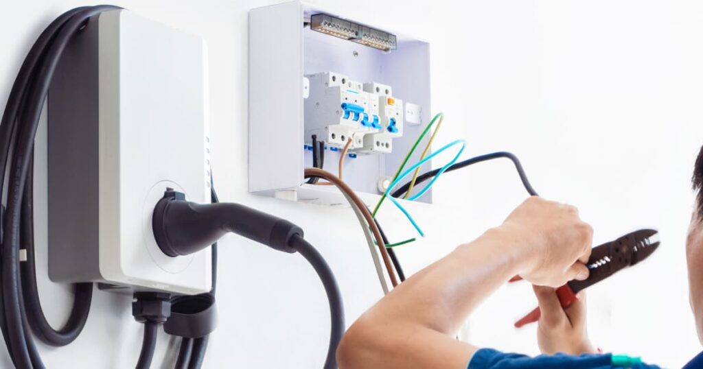 Een vakman die bezig is met de bedrading van een thuisbatterij te installeren.