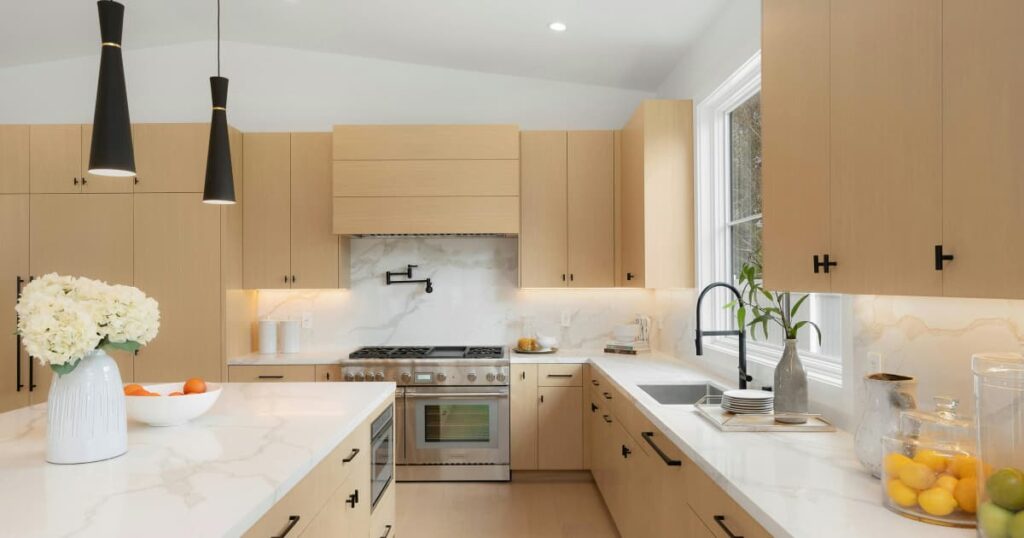 Een L-vormige beige keuken met een marmeren keukenwerkblad en marmeren eiland. 