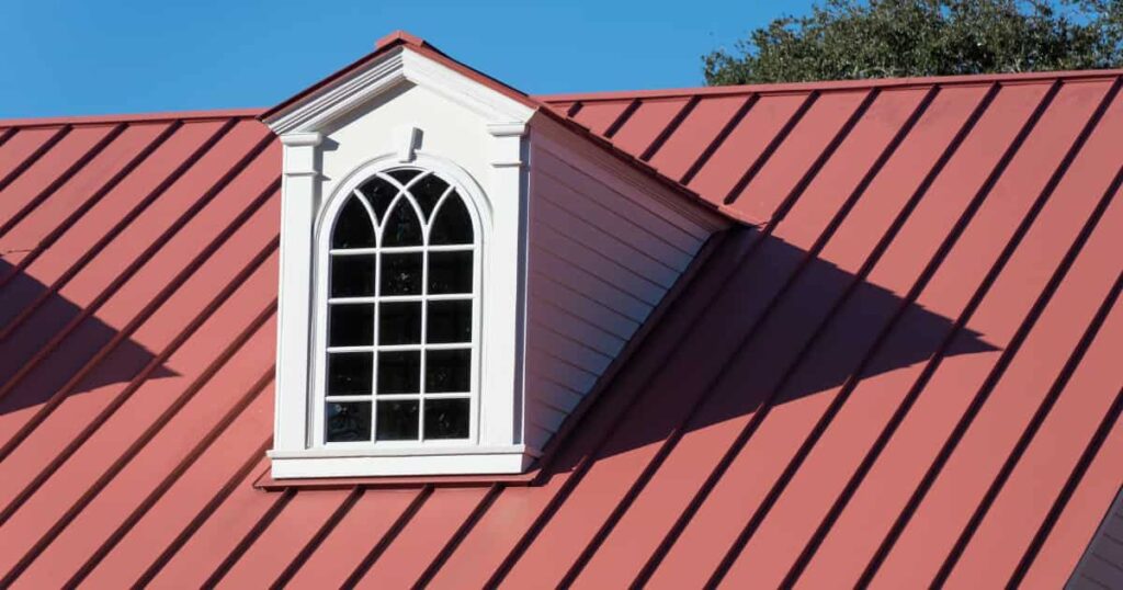 Een dakkapel in het wit op een rood hellend dak.