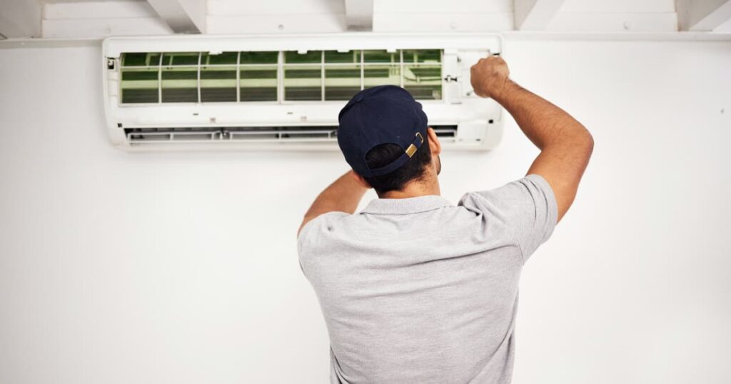 Een werkman die aan airco monteert. 